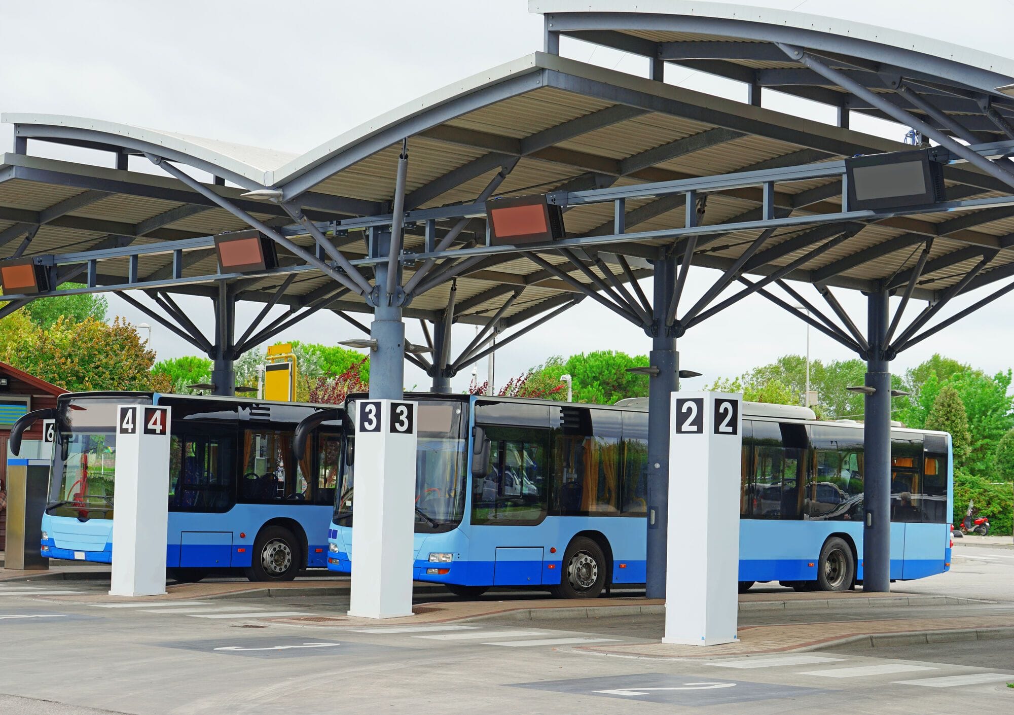Trois bus bleus sont alignés sous un abri dans une gare routière.